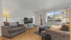 A modern living room with a flat-screen TV, two sofas, a coffee table, and a lamp. - Pool & Hot Tubs | Nextdoor to Pickleball | Air Conditioning (Steamboat Springs)