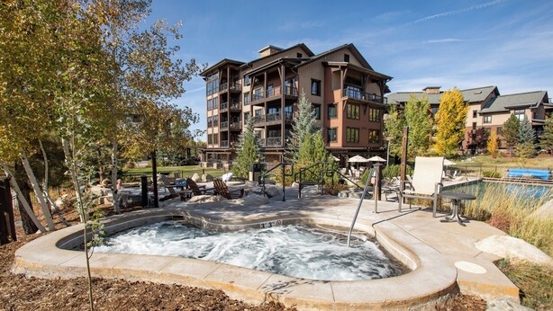 A hot tub area with a pool, surrounded by outdoor seating and a building with multiple balconies. - Pool & Hot Tubs | Nextdoor to Pickleball | Air Conditioning (Steamboat Springs)
