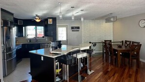 A modern kitchen with a central island, stainless steel appliances, and a dining area with wooden chairs and a table.