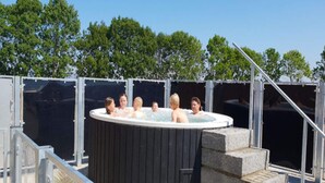 A hot tub with six people, surrounded by a metal fence and stone steps. - 5 Person Holiday Park Home in Holbaek (Holbaek)