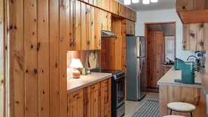 Eine Küche mit Holzausstattung, einem Herd, einem Kühlschrank und einer Spüle.
