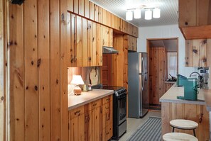 A kitchen with wooden cabinets, a stove, a refrigerator, and a sink.