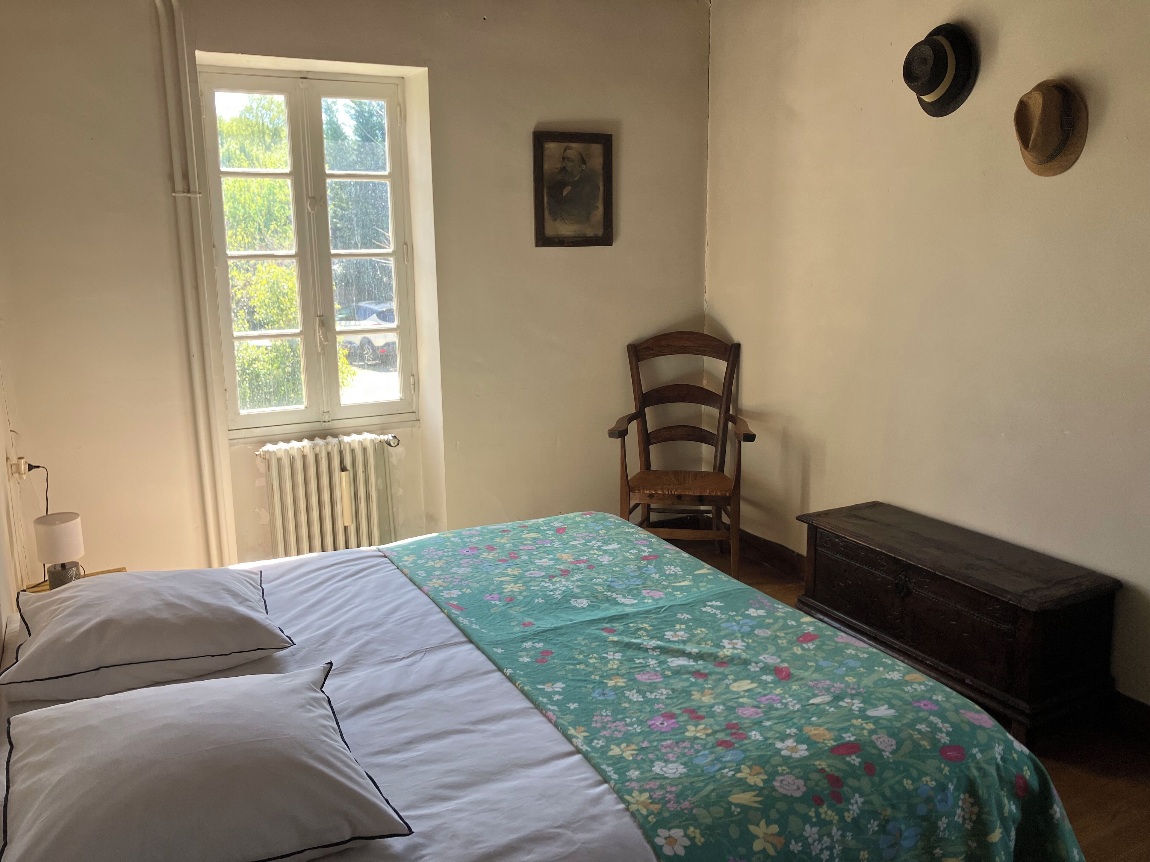 Ein Schlafzimmer mit einem Bett, einem Sessel, einer Heizung und einer Kommode.
