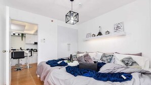 Une chambre à coucher comprenant un lit, une table de chevet, une lampe et une étagère murale décorative.