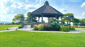 A gazebo with a green roof and a small tower, surrounded by a well-maintained lawn and flowering plants. - Welcome to The Perfect Break — Your Cozy Coastal Getaway! (Lavallette)