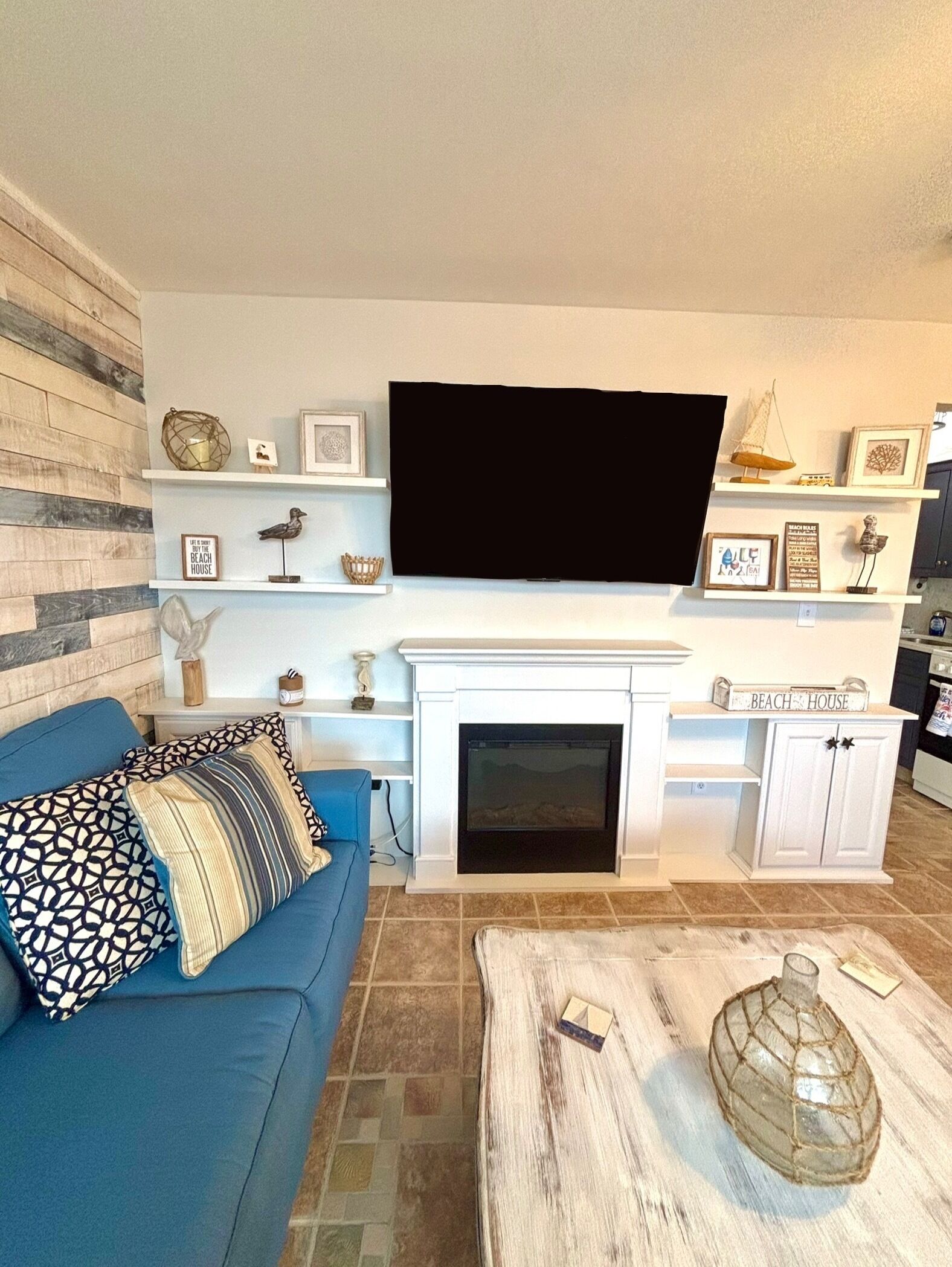 Een woonkamer met een blauwe bank, een openhaard en een tv aan de muur.