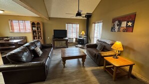 A living room with two leather sofas, a wooden coffee table, a TV, and a lamp. - Beautiful Cabin with Hot Tub (Alto)