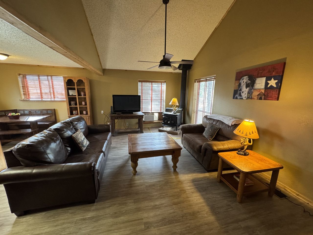 A living room with two leather sofas, a wooden coffee table, a TV, and a lamp.