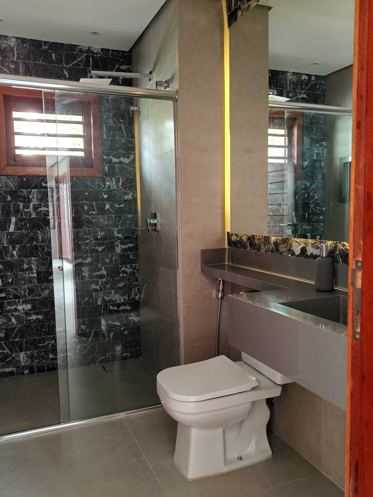 A modern bathroom with a glass-enclosed shower, a white toilet, and a marble backsplash.