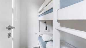Une chambre avec un lit superposé, une porte, une douche et un porte-serviettes.