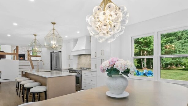 A modern kitchen with a central island, pendant lights, and a view of the outdoors. - Renovated Retreat with Heated Pool (Redding)
