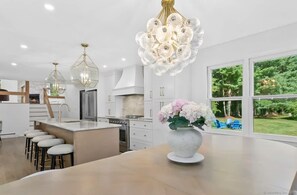 A modern kitchen with a central island, pendant lights, and a view of the outdoors. - Renovated Retreat with Heated Pool (Redding)