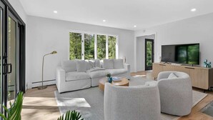 A modern living room with a sectional sofa, a coffee table, and a TV. - Renovated Retreat with Heated Pool (Redding)