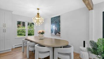 A dining area with a wooden table, white chairs, a chandelier, and artwork on the walls.