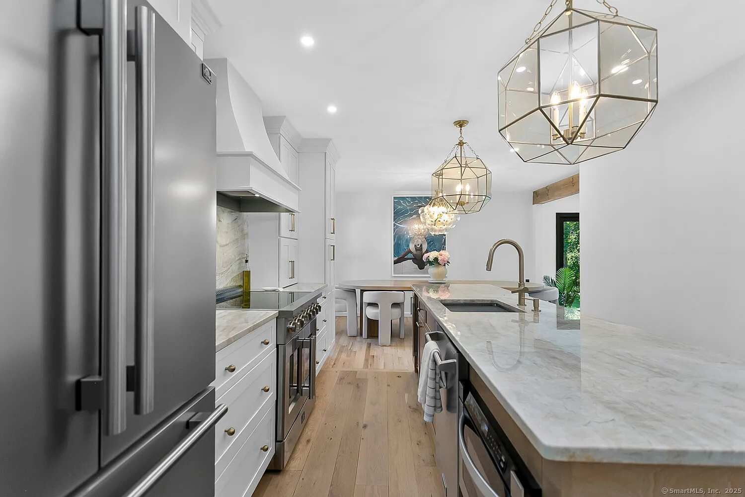A modern kitchen with stainless steel appliances, a marble countertop, and a central island.