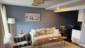 A living room with a sofa, armchair, coffee table, and a painting on the wall. - Coastal modern 2-bedroom condo in lovely Wells with water views (Wells)
