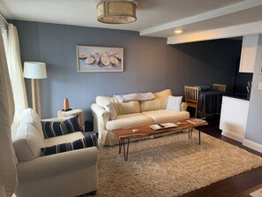 A living room with a sofa, armchair, coffee table, and a painting on the wall. - Coastal modern 2-bedroom condo in lovely Wells with water views (Wells)