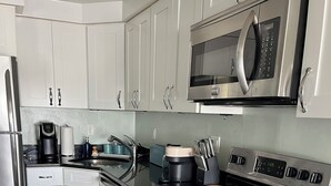 A modern kitchen with stainless steel appliances, white cabinetry, and a built-in microwave. - Coastal modern 2-bedroom condo in lovely Wells with water views (Wells)
