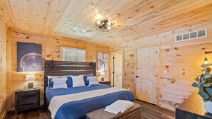 Une chambre dans une cabane en bois, avec un lit, des tables de chevet, un banc et un luminaire au plafond.