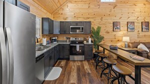Une cuisine moderne avec des meubles de couleur sombre, des appareils électroménagers en acier inoxydable et un plafond en bois.