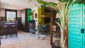 A modern kitchen with a bar area, green walls, and a large plant.