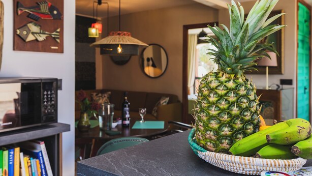 A dining area with a table set for two, featuring a pineapple and bananas on the table.