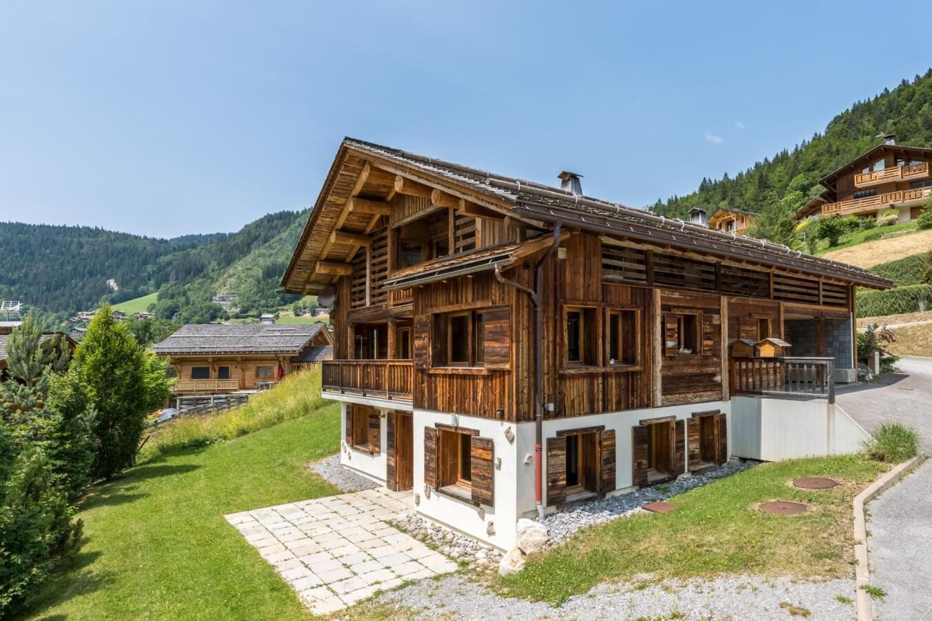 A wooden chalet with a balcony, set in a mountainous area.