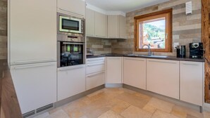Una cocina moderna con horno integrado, microondas y ventana con vistas a la vegetación.