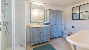 Un baño con ducha, lavabo con espejo, inodoro y bañera.