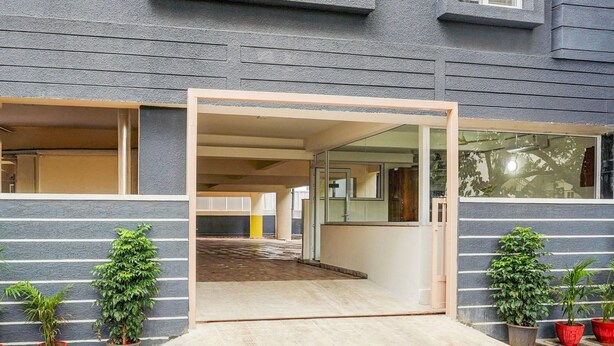 Une entrée d’immeuble avec une porte en verre, des plantes en pot et un sol carrelé.