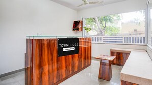 Un comptoir d’accueil avec une enseigne indiquant « TOWNHOUSE », une cloison en verre, un ventilateur de plafond et une fenêtre donnant sur des arbres.