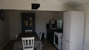 A small kitchen with a dining table and chairs, a refrigerator, a stove, and a cabinet with glass doors.