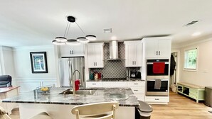 A modern kitchen with white cabinets, a stainless steel refrigerator, a built-in oven, and a granite countertop. - Peaceful Mableton Retreat Near Atlanta’s Vibrance (Mableton)