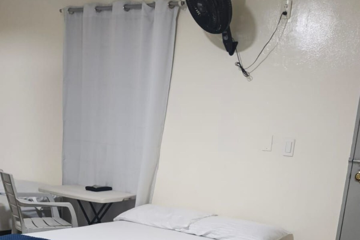 Una habitación pequeña y limpia con una cama, un escritorio y una silla.