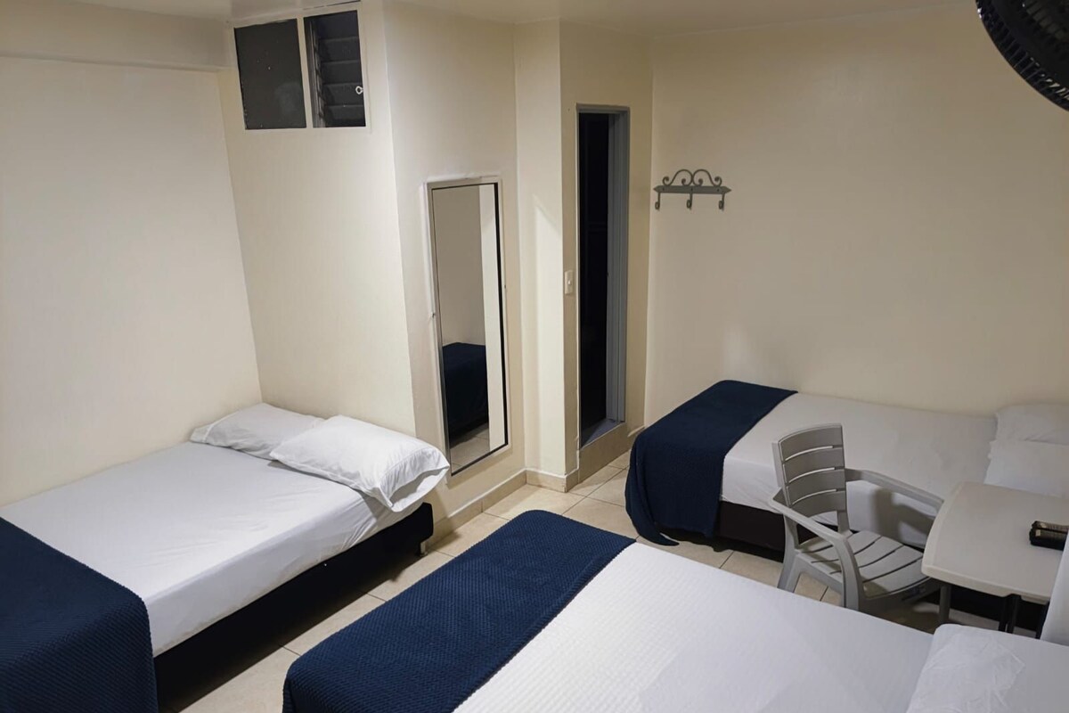 Een hotelkamer met twee eenpersoonsbedden, een klein bureau en een stoel.