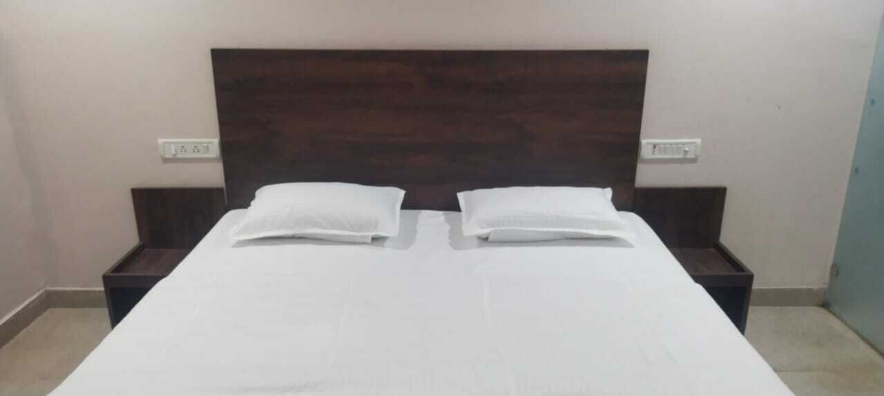 A bed with white bedding, two pillows, and a wooden headboard.