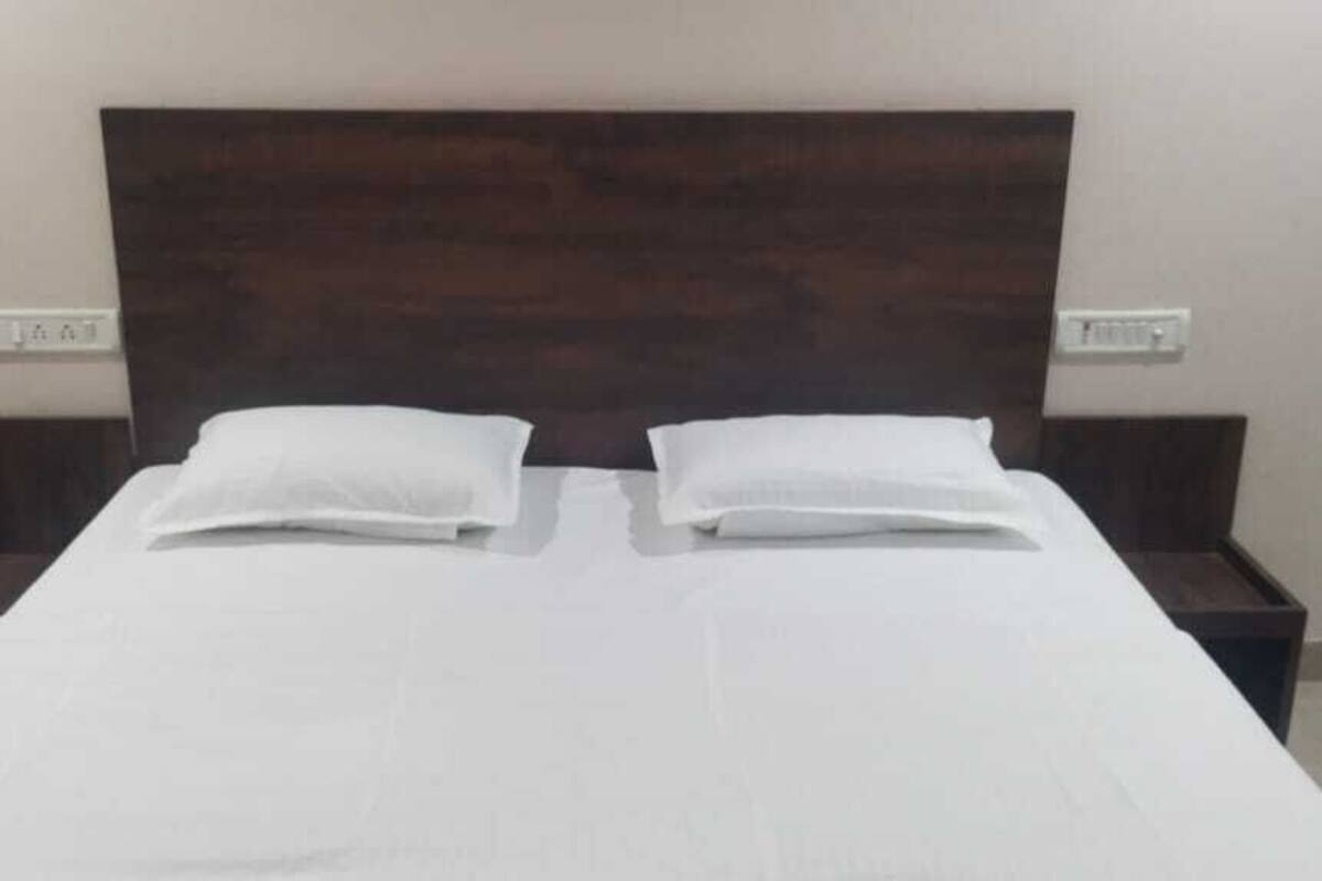 Una cama con ropa blanca, dos almohadas y cabecera de madera.