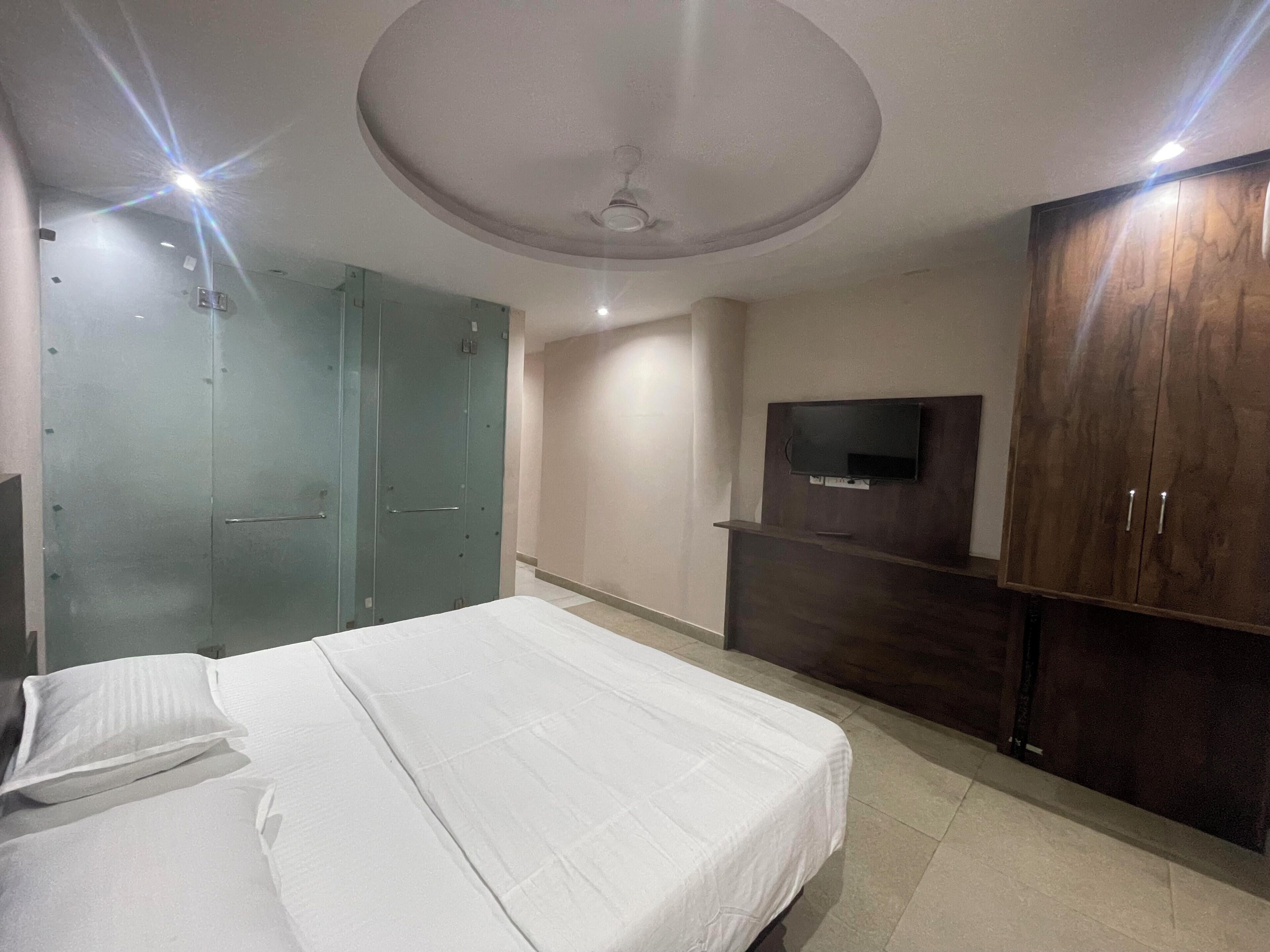 A bedroom with a bed, a wardrobe, a television, and a ceiling fan.