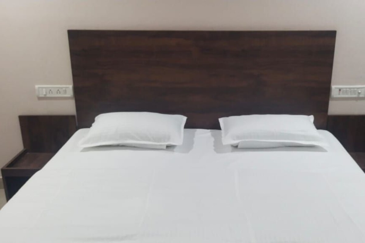 A bed with white bedding, two pillows, and a wooden headboard.