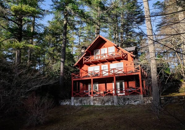 A cabin with a balcony, surrounded by trees.