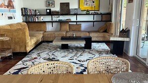 A living room with a wooden floor, a sofa set, a coffee table, and a bookshelf. - Relaxing house with spacious dock tucked on Gordon River. Live the Florida dream (Naples)