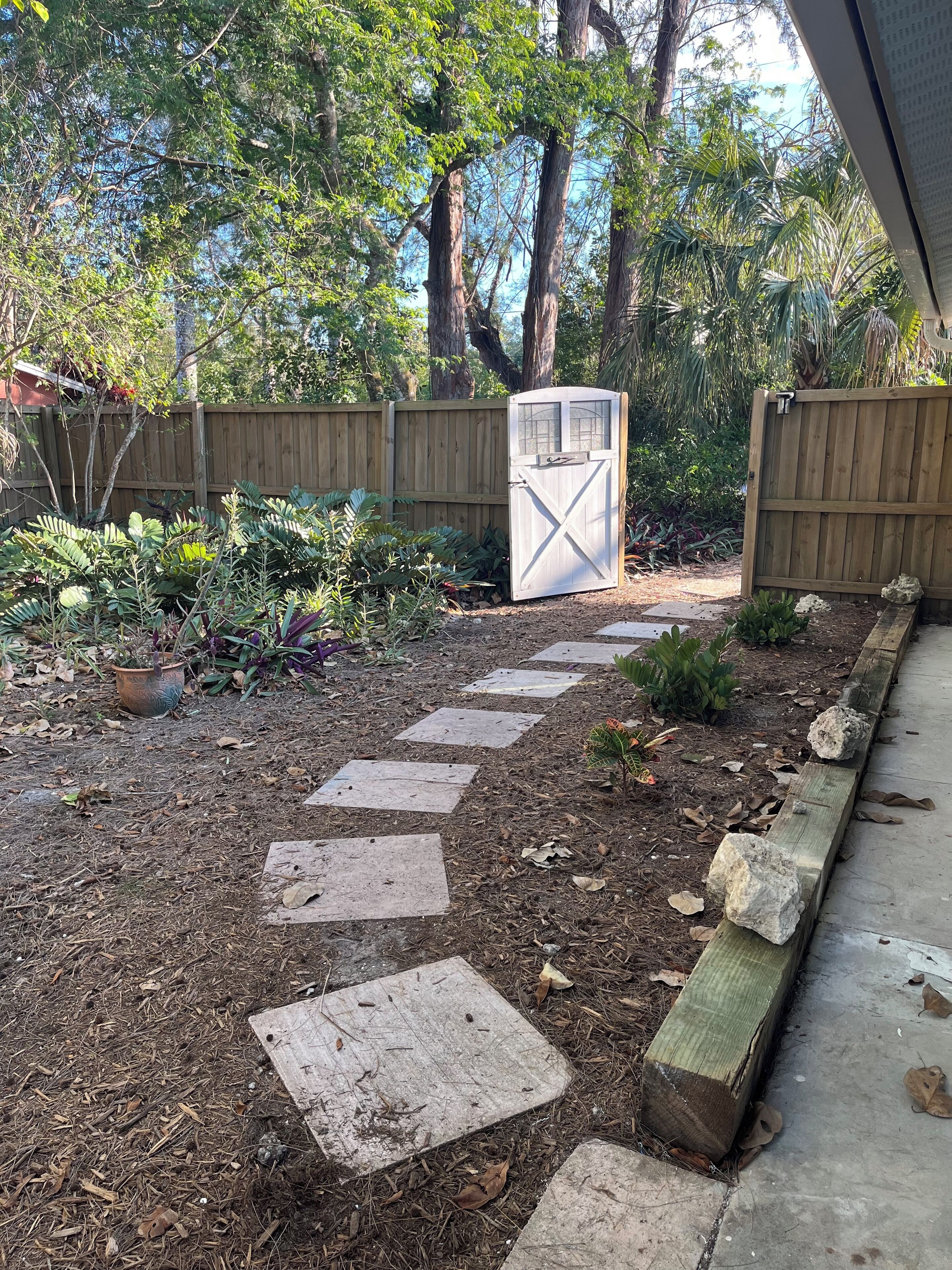 A garden pathway with stepping stones leading to a wooden gate.