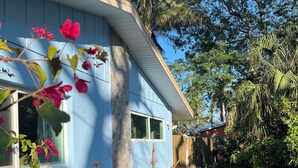 A house with a blue exterior, a front porch, and a garden with red flowers. - Relaxing house with spacious dock tucked on Gordon River. Live the Florida dream (Naples)