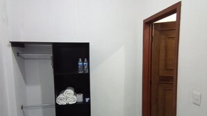A small room with a black wardrobe, a wooden door, and a blue tiled floor. - Posada Antonia (Bacalar)