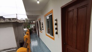 A corridor with a blue tiled floor, wooden benches, and a wooden door. - Posada Antonia (Bacalar)