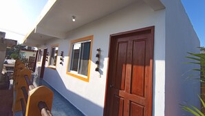 A building with a white exterior, a wooden door, and a window with a wooden frame. - Posada Antonia (Bacalar)