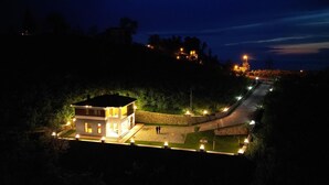 A modern two-story building with a well-lit exterior, surrounded by a landscaped garden and a curved driveway. - Çiftlikte Konaklama Villa Saklı Bahçe (ordu)