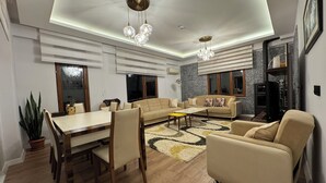 A modern living room with a dining area, a sofa set, a coffee table, and a chandelier. - Çiftlikte Konaklama Villa Saklı Bahçe (ordu)