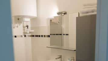 Une salle de bain équipée de toilettes, d’un lavabo, d’un miroir et d’un meuble de rangement.