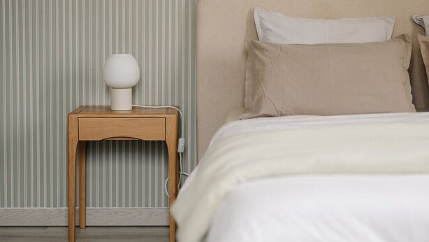 Ein Schlafzimmer mit einem Bett, einem Nachttisch und einer Lampe.